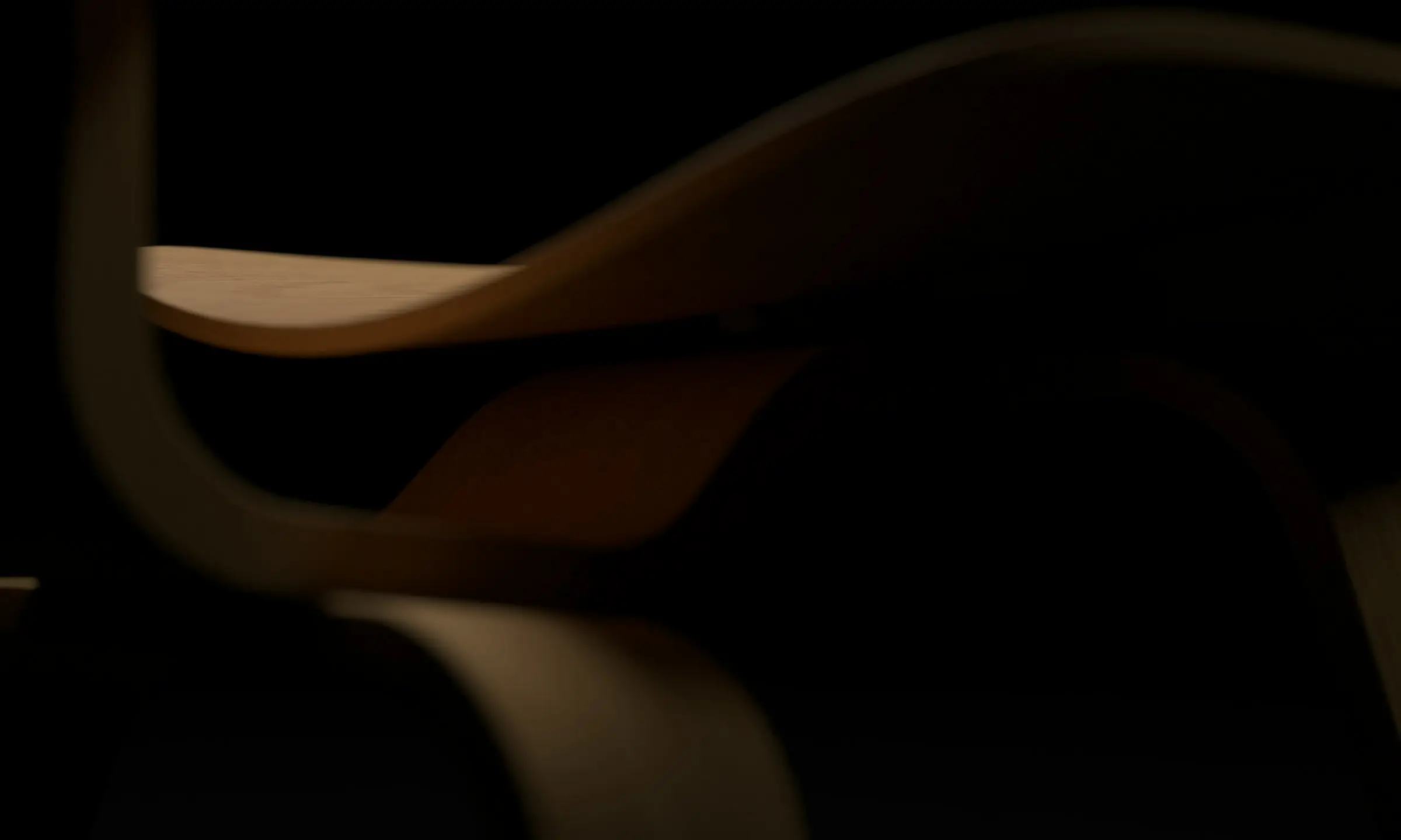 A moulded plywood chair, lit softly against a dark background